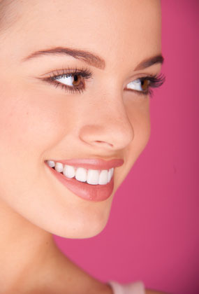 A woman smiles a beautiful smile. Regular teeth cleanings protect the health and beauty of your smile.