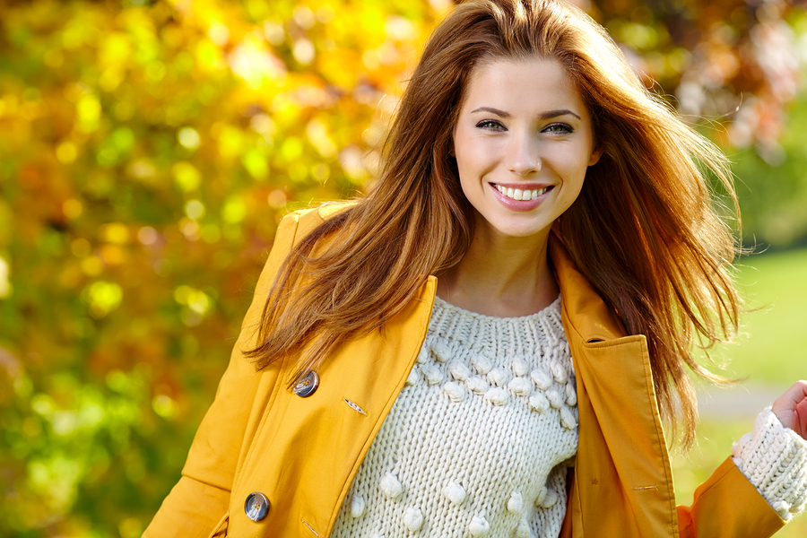A woman smiles, her smile beautifully aligned. Clear aligners (like Invisalign) can straighten teeth invisibly.