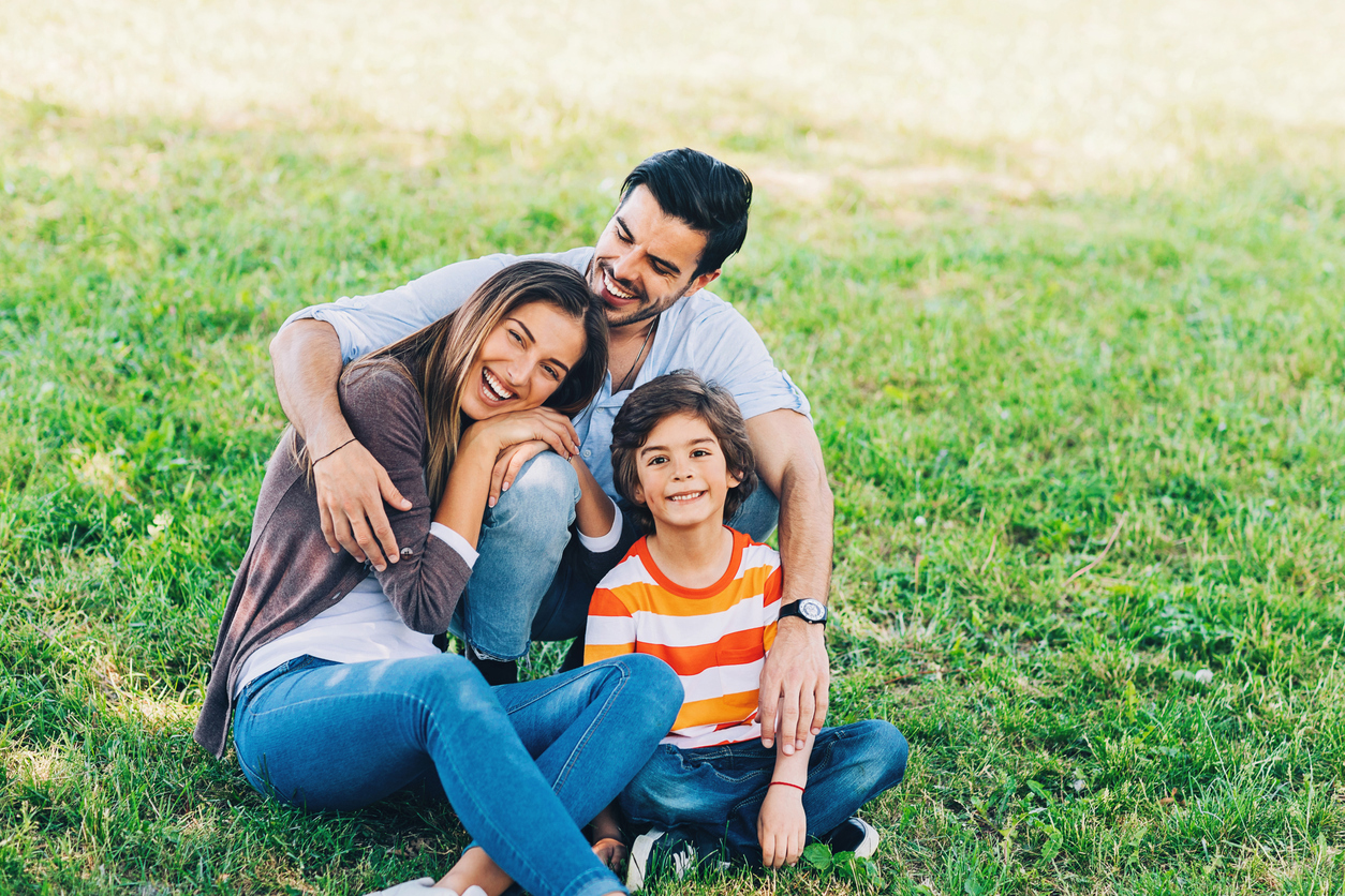 Photo of a family sitting on the grass. The dentists at Mountain View Family Dental provide care for children and adults.