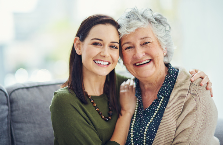 A young woman and an older woman smile.